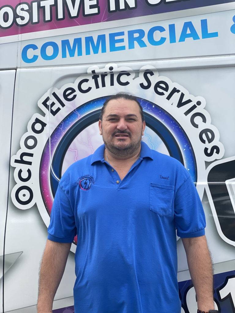 Licensed Electrician David from Ochoa Electric Services stands beside the company van in Port St. Lucie. We specialize in panel upgrades and electrical installations.